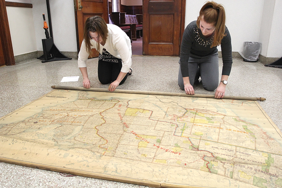 KAREN VIBERT-KENNEDY/Sun-Gazette A 19th century map of the United States, which contains entries such as the Louisiana Purchase from France, is inspected in the foyer of the second floor outside of City Council chambers by city employees. At left, Chelsea Myers, city planner, looks over most of the western U.S. while Rebecca Haladay, city engineer and assistant general manager of the public works department, inspects the eastern U.S., which still was listed as 